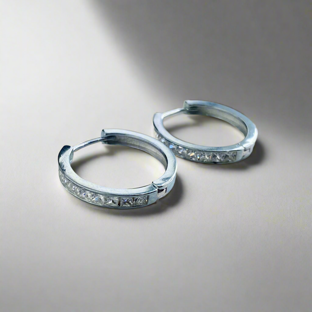 Studio image of the Lustrous Platinum Hoop Earrings with zircon embellishments, elegantly displayed on a soft reflective surface.