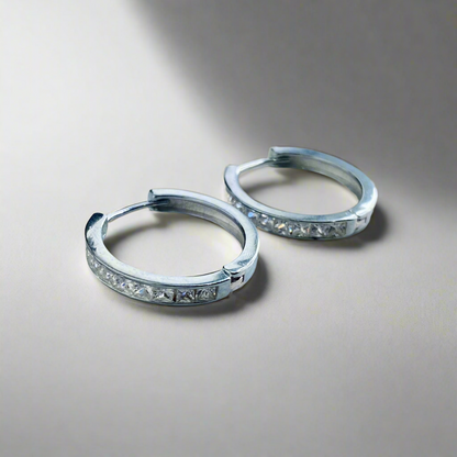 Studio image of the Lustrous Platinum Hoop Earrings with zircon embellishments, elegantly displayed on a soft reflective surface.