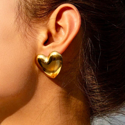 Close-up of a woman wearing gold heartbeat stud earrings, showcasing their elegant design.