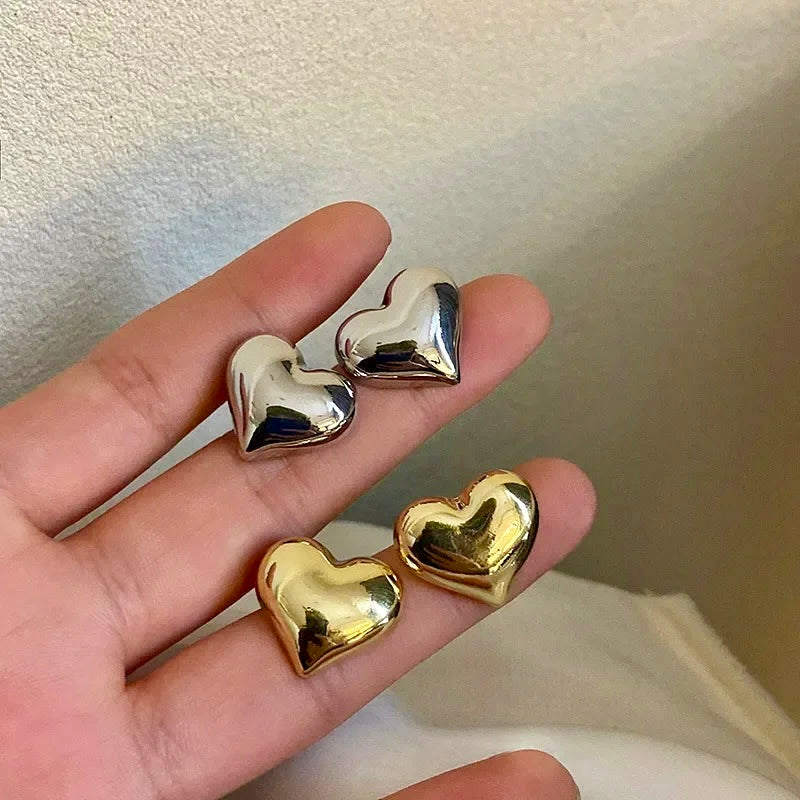 Side-by-side display of gold and silver heartbeat stud earrings, offering versatile style choices.