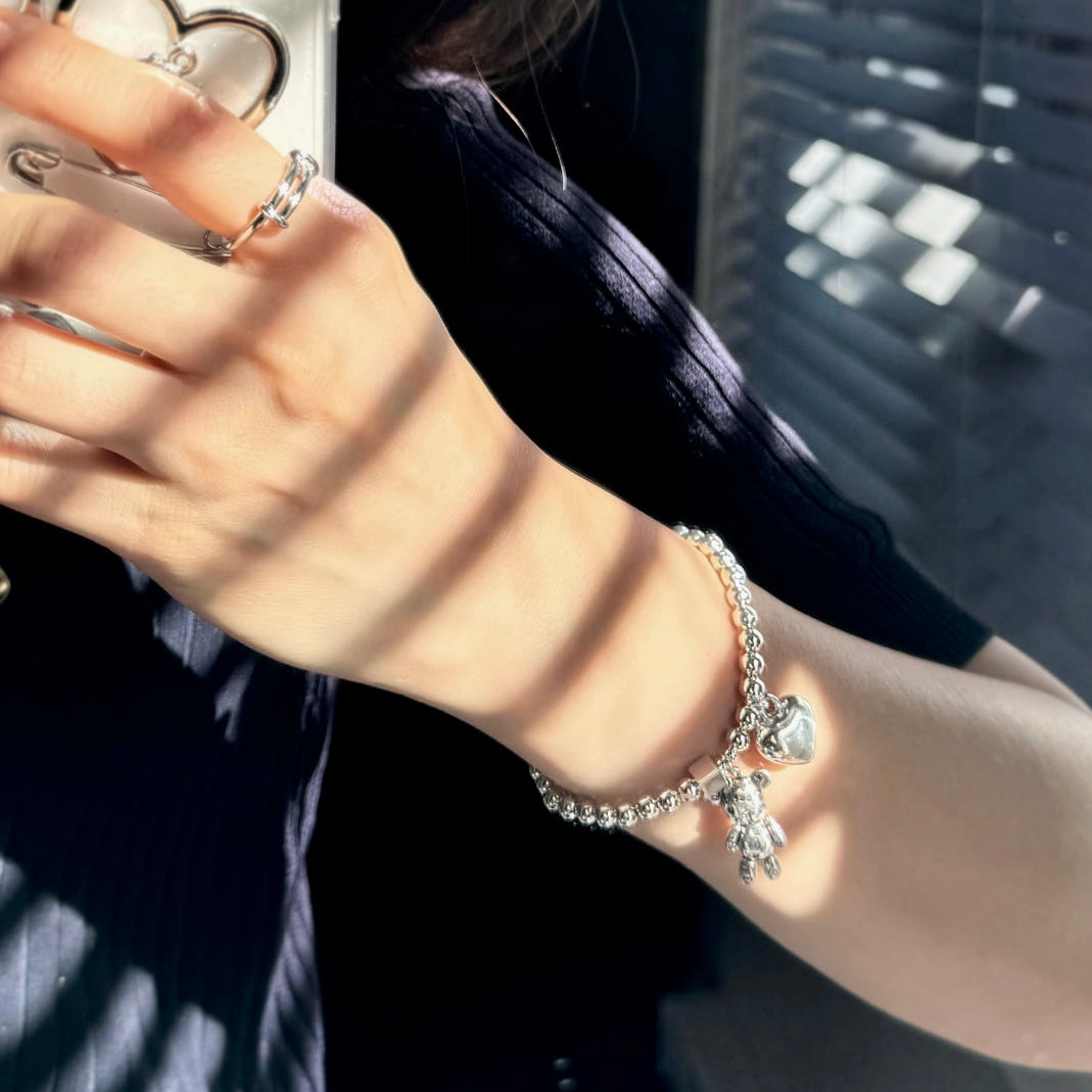 Hand wearing the Love & Peace Teddy Charm Bracelet, showcasing the trendy sterling silver design and zircon accents.