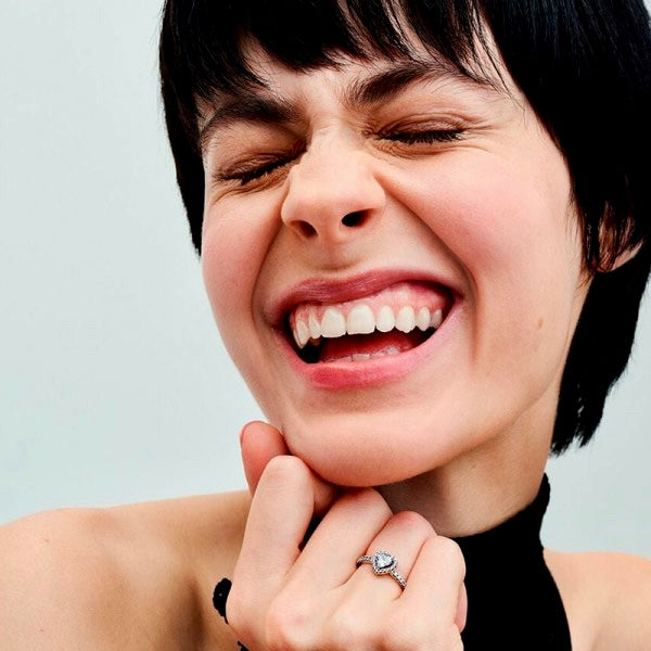 Smiling woman wearing the Radiance Wishbone Ring, highlighting its elegant wishbone design.