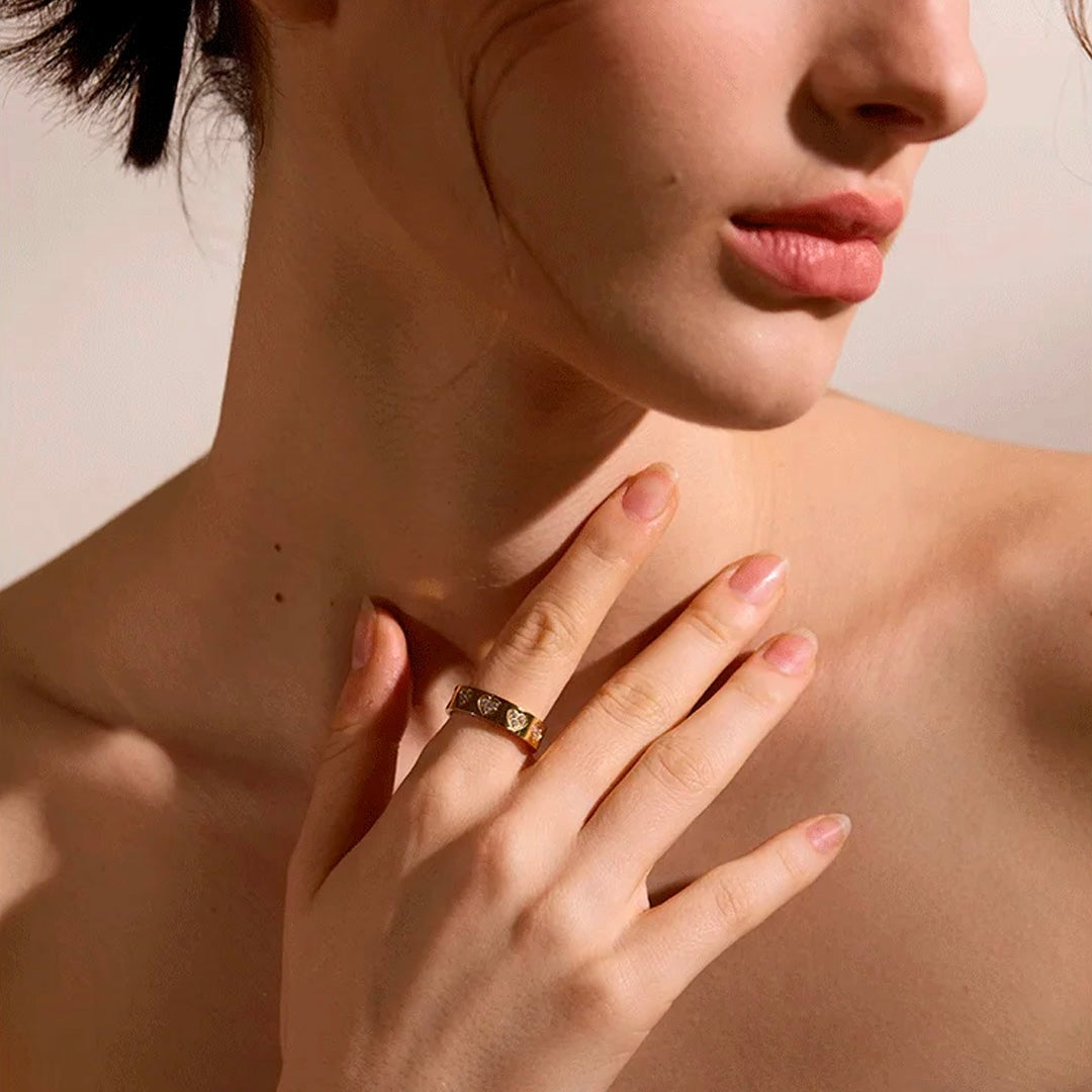 Close-up of a model wearing the Seraphine Halo Ring in gold, elegantly posed with hand on chest.