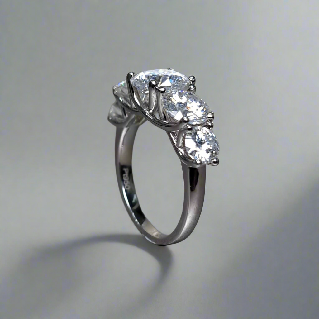 Close-up of a silver 5-stone engagement ring with round-cut moissanite gemstones.