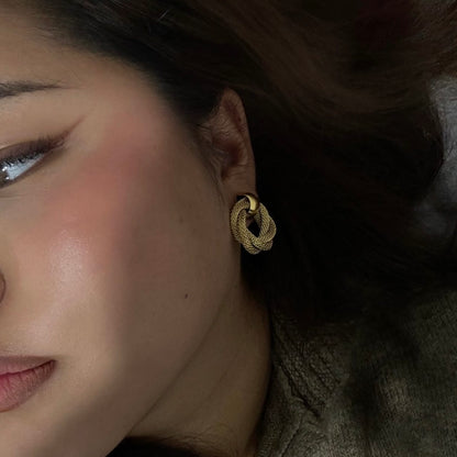 Side view of a woman wearing the golden Twisted Statement Earrings, highlighting their lightweight and stylish design.